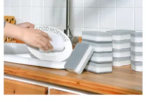 Kitchen cleaning sponge block detail showing double-sided scouring pad in use at sink.