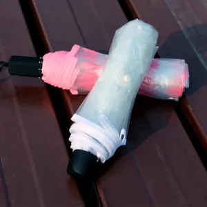 Kompakter Faltschirm mit klarem Schneeflockenbezug und pinkem Design fur den Alltag.