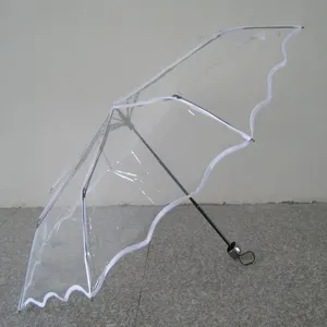 Transparent folding umbrella detail showing clear POE material and delicate white lace scalloped edge.