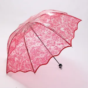 Close-up detail of the red lace transparent folding umbrella featuring delicate floral heart patterns.