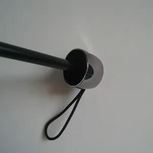 Folding umbrella handle detail closeup showing black strap and metallic cap design.
