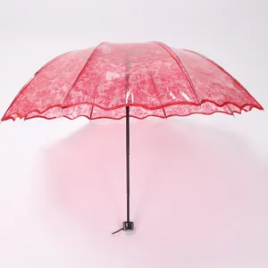 Detailed view of the red transparent folding umbrella featuring delicate lace and heart patterns.