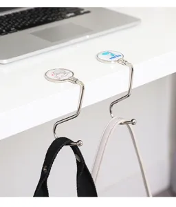 Detail shot of portable folding desk purse hook hanging on table edge holding bags with cute design
