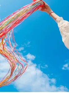 Detailed view of colorful hand thrown wedding ribbons flying dynamically in the bright open sky.