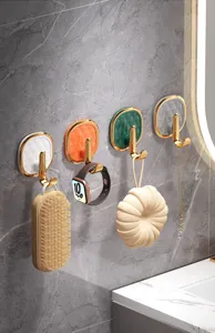 Detailed view of luxury adhesive wall hooks with geometric texture and gold finish holding daily items.