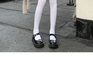 Detailed shot of white tights and black platform Mary Jane shoes, stylish street fashion.