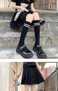 Detailed view of women black knee high socks with white stripes, stylish and comfortable.