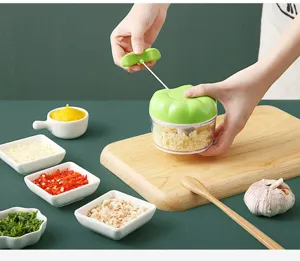 Manual garlic chopper detailed view showing pull string operation on cutting board with ingredients.