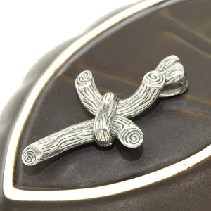 Stainless steel branch cross pendant detail view, unique textured jewelry close up.