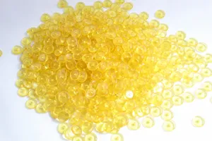 Dettaglio in primo piano di perline distanziere in resina gialla per creazione di gioielli.
