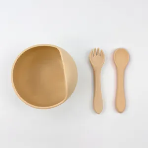 Silicone baby feeding set featuring a slanted bowl, ergonomic fork and spoon for toddlers.