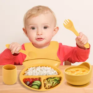 Toddler silicone feeding set detail in use, featuring divided plate, bowl and baby cup.