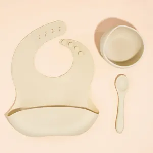 Baby silicone feeding set including bib, bowl and spoon in beige color for toddlers.