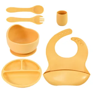 Baby silicone feeding set with suction plate, partitioned bowl, bib, spoon, fork, and cup.