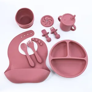 Silicone baby feeding set with divided plate, bib, spoon, fork and cup for toddler mealtime.