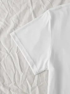 Close-up detail of a plain white short-sleeve t-shirt showing fine fabric texture and neat stitching.