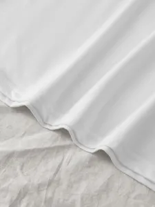 Close-up view of white solid color cotton t-shirt fabric texture and neat hem stitching.