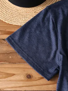 Close-up detail of dark blue short sleeve t-shirt fabric texture on wooden board background.