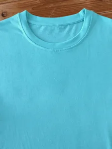 Turquoise blue cotton t-shirt detail showing round neck and smooth fabric texture.