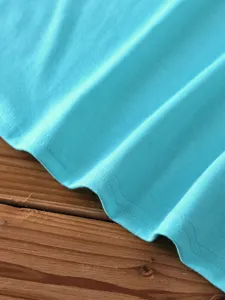 Turquoise cotton t-shirt fabric detail, fine stitching and soft texture close-up.