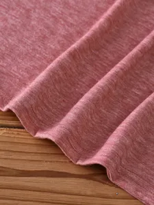 Close-up detail of soft red heather cotton t-shirt fabric showing neat stitching and texture.