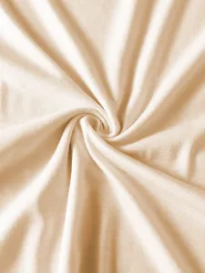 Detailed view of soft beige cotton fabric texture, breathable jersey knit material close up