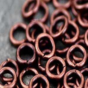 Close-up detail shot of red copper metal jump rings, ideal for DIY jewelry making accessories.
