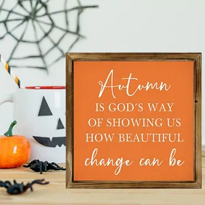 Close-up detail of the autumn wooden sign with inspirational quote, orange backdrop, rustic prop styling.