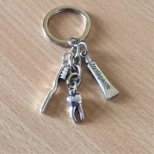 Detailed shot of metal dentist keychain charms including toothbrush, tooth, and toothpaste pendant.