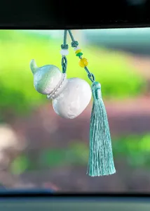 Close-up van een decoratief pompoenvormig auto-hangend ornament met een elegante cyaan kwast.