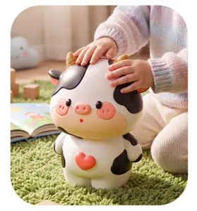 Detail shot of the cute cartoon cow piggy bank featuring a sweet heart and black spots.