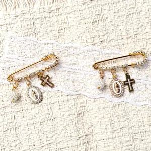 Gros plan sur la broche épingle dorée élégante avec pendentif perle et croix raffiné.