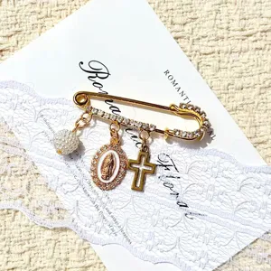 Broche épingle de sûreté dorée vintage élégante avec perle, pendentif et croix.