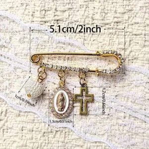 Gros plan détaillé de broche épingle de sûreté dorée vintage avec strass, perle et pendentif croix.