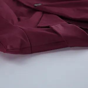 Primo piano dettagliato del blazer bordeaux che mostra sartoria fine e tessuto liscio.