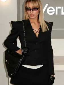 Giacca blazer nera da donna con vita stretta e orlo asimmetrico per la moda autunnale.