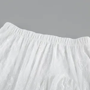Vista dettagliata della gonna in pizzo bianco con vita elastica e delicato tessuto trasparente.