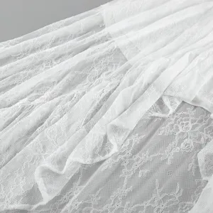 Dettaglio del tessuto della gonna in pizzo bianco con delicati motivi floreali.