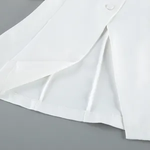 Close up view of the white blazer detail showcasing the elegant hem, slit and button design.