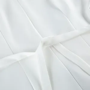 Elegant white blazer detail showcasing the stylish waist belt and refined seam texture.