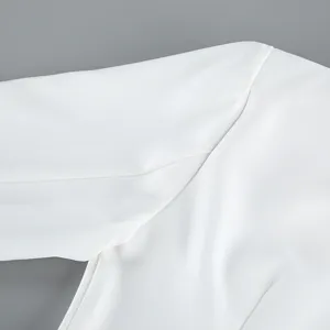 Close-up detail of white blazer shoulder seam, fine tailoring and clean fabric texture.
