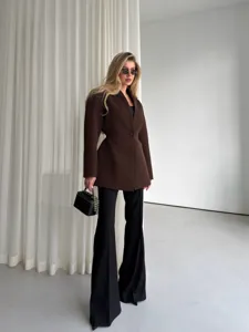 Detail shot of stylish brown V-neck tailored blazer paired with black trousers and bag.