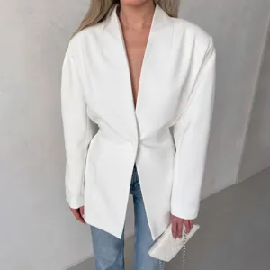 Close-up detail of the white tailored blazer featuring cinched waist and V-neck.