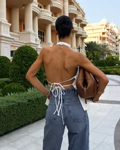 Detailed view of a sexy backless halter top featuring lace-up straps and classic denim jeans.