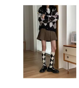 Detail view of argyle knit cardigan and classic plaid socks in a cozy indoor lifestyle setting.
