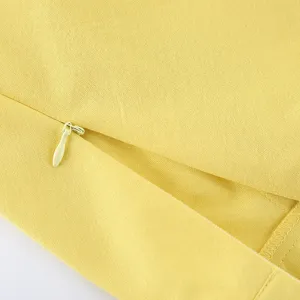 Detaillierte Nahaufnahme von gelbem Stoff und feinem Reißverschluss für Damenbekleidung.