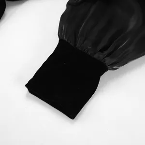 Vista detallada de la manga del vestido negro con puño de terciopelo suave y tela brillante.