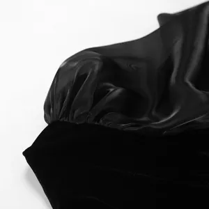 Detalle de vestido de terciopelo negro con manga abullonada transparente y textura suave.