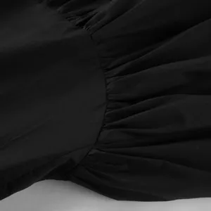 Primo piano dettaglio della gonna asimmetrica nera in cotone con vita alta e volant.