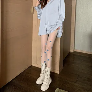 Detail shot of sheer white tights featuring vibrant blue butterfly print and slim leg design.
